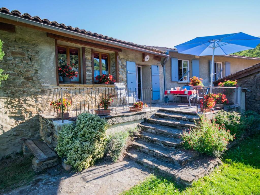 Casa con patio con mesa y sombrilla en Gite des Kathares, en Villeneuve dʼOlmes