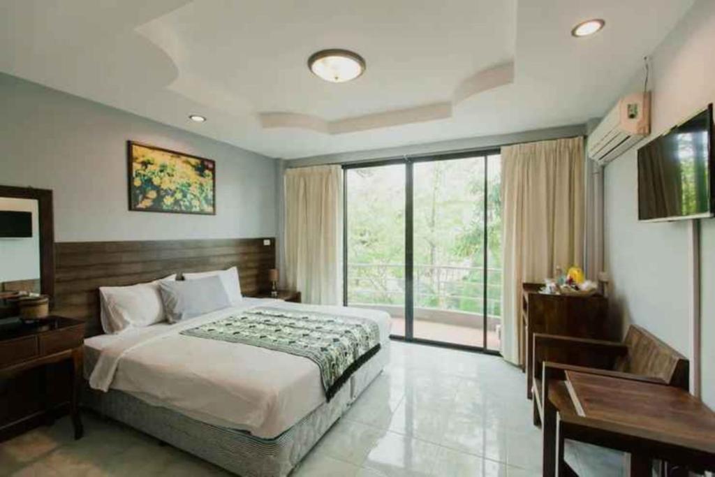 een slaapkamer met een bed, een bureau en een raam bij Platinum Place in Bangkok