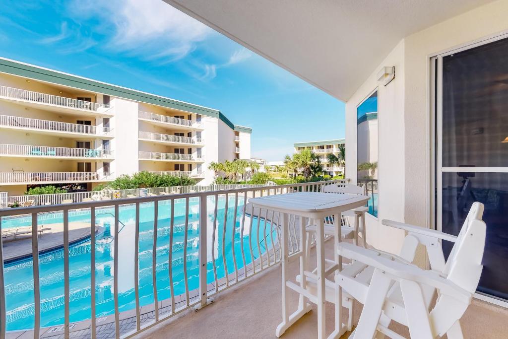 a balcony with a table and chairs and a swimming pool at Dunes of Seagrove A104 in Santa Rosa Beach