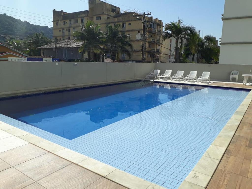a large swimming pool with chairs on a building at Apartamento 500m Praia da Enseada Guarujá varanda e vaga de garagem in Guarujá