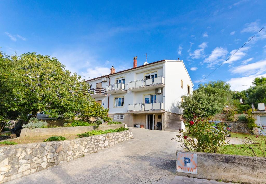 a large white building with a stone wall at Apartment Ivanka in Banjol