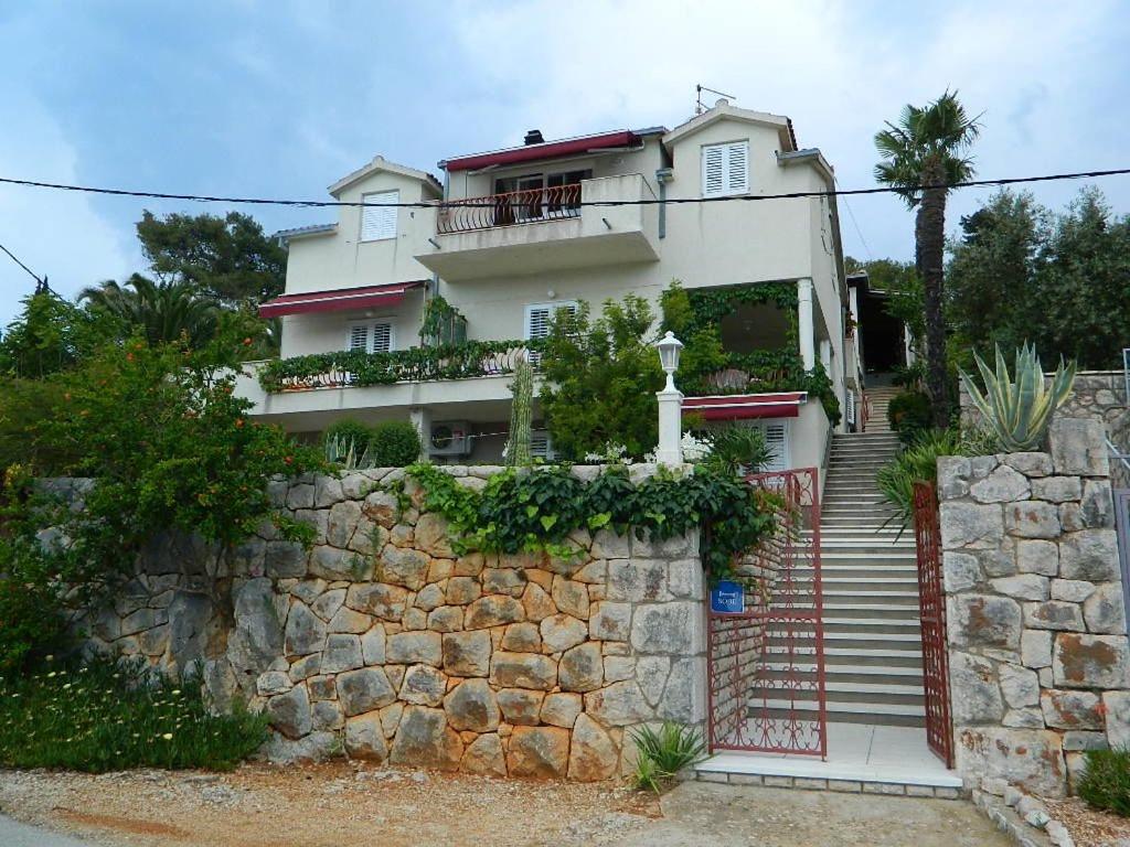 a white house with a stone wall and stairs at Apartments and Rooms Darinka in Vrboska