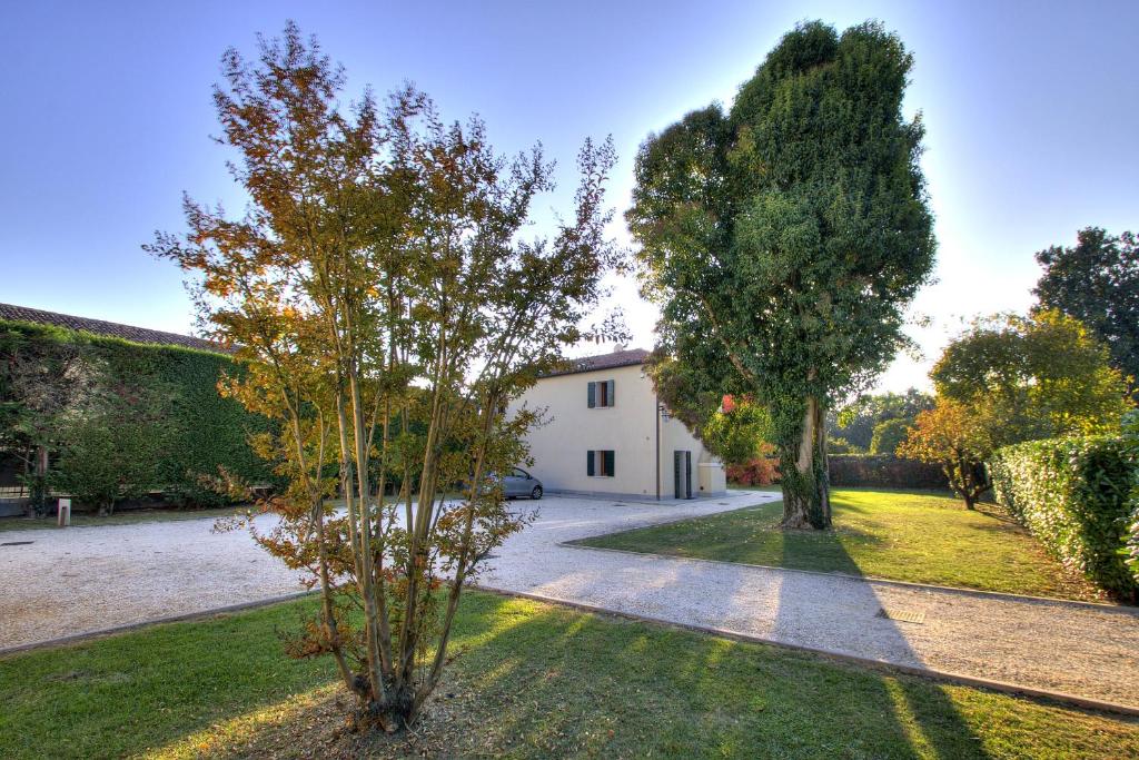un jardin avec deux arbres et un bâtiment blanc dans l'établissement TORRE-BARBARIGA country house,3 beds,3 bath,parking, à Stra
