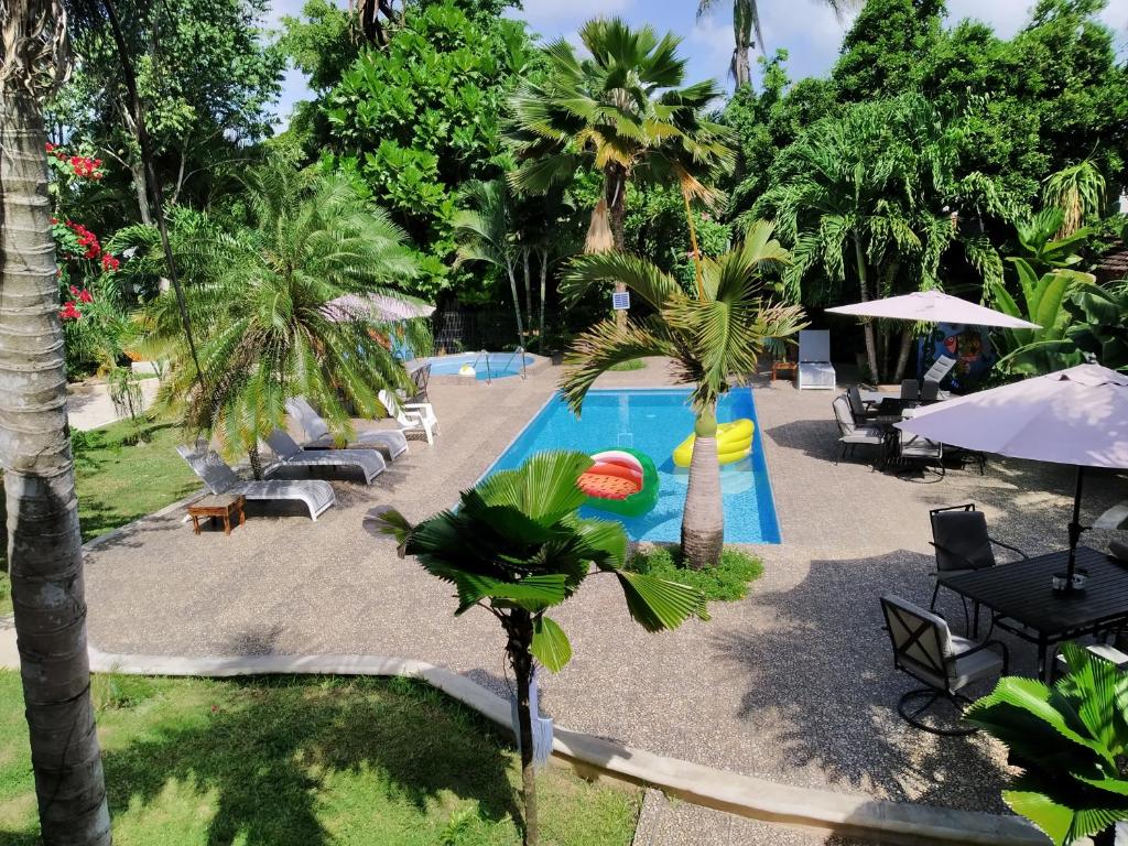 an outdoor swimming pool with palm trees and tables at Hotel Henry Bacalar in Bacalar