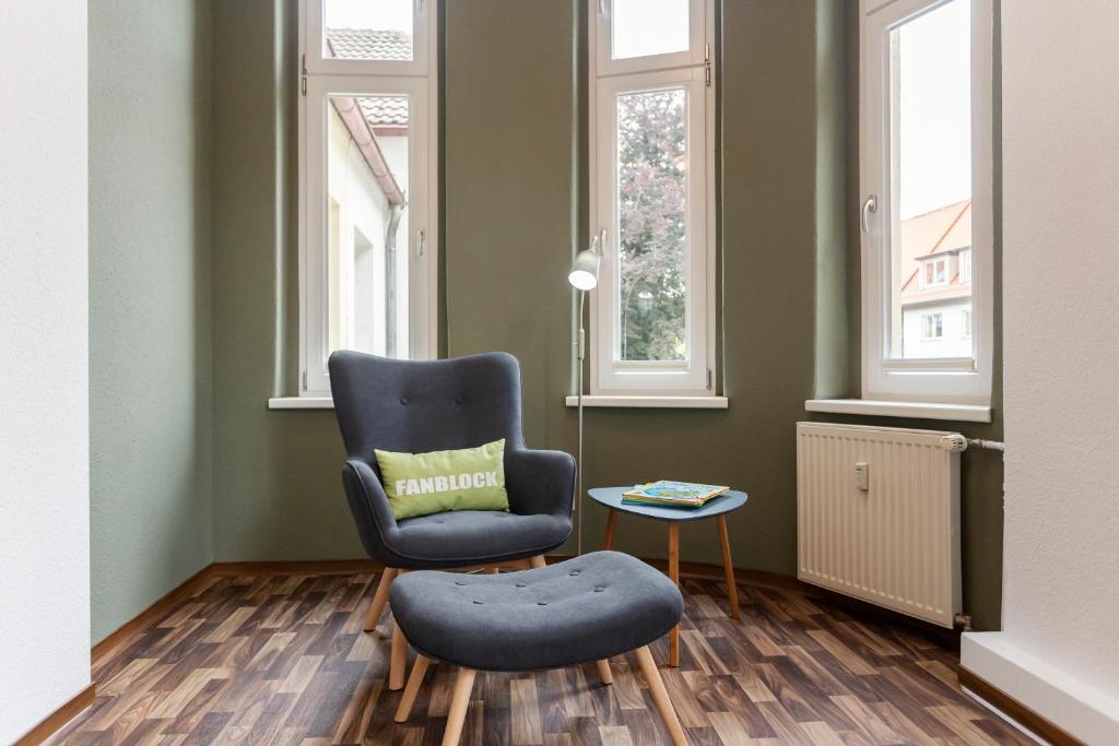 una sedia e un pouf in una stanza con finestre di WR Grüne Ferienwohnung in der alten Apotheke a Wernigerode