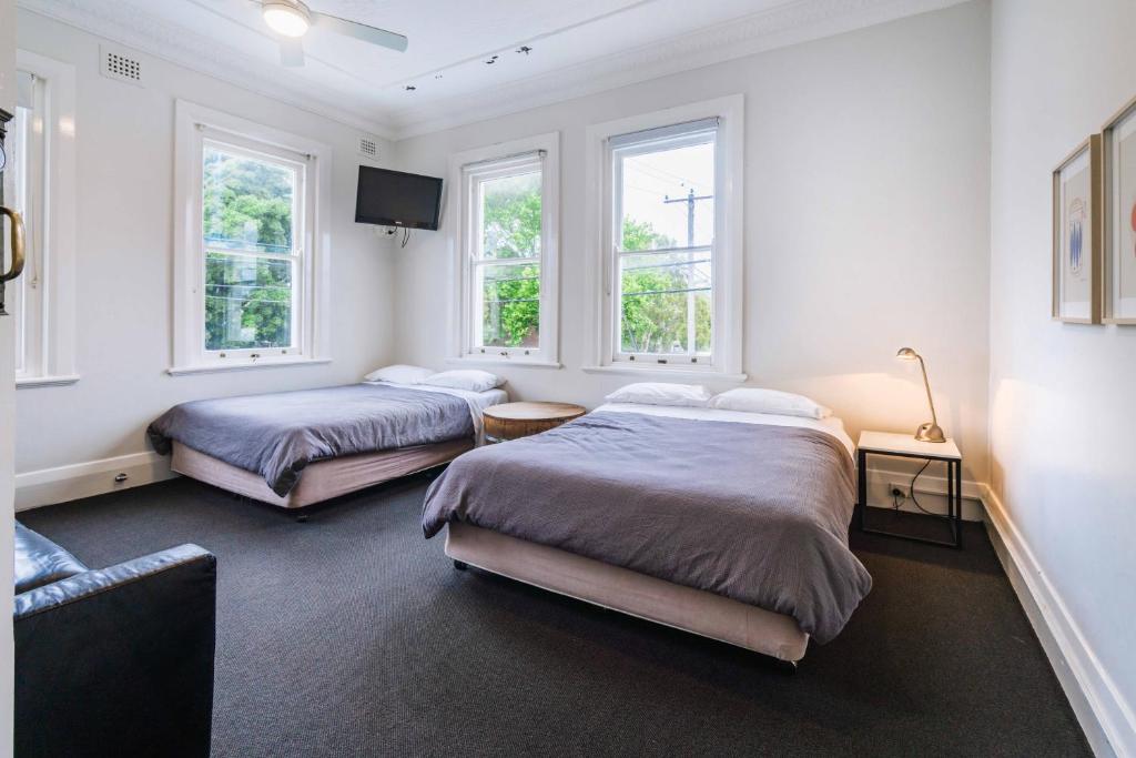 two beds in a room with two windows at The Oriental Hotel in Newcastle