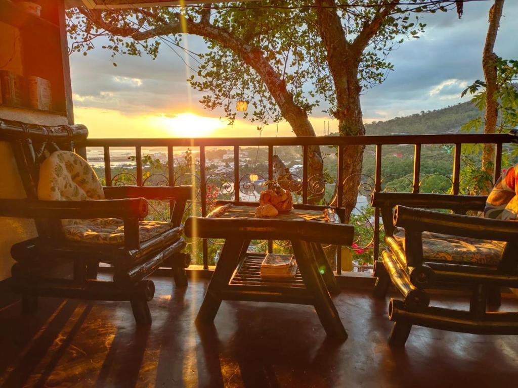 a porch with a table and two chairs and the sunset at Purple Homestay in Coron