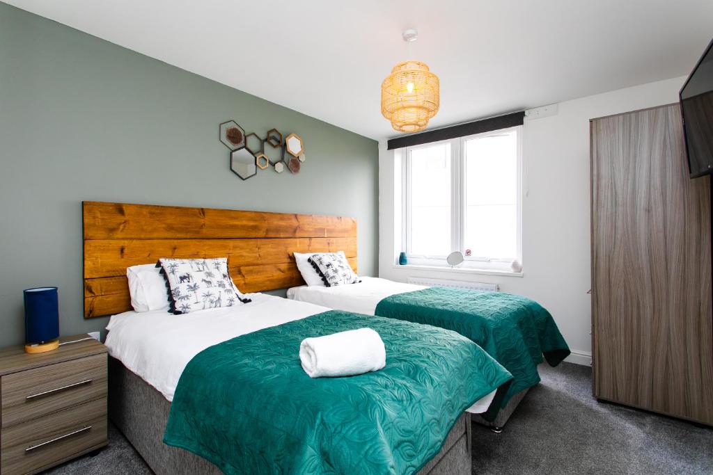 a bedroom with two beds with green and white sheets at Portland Apartments 198 by #ShortStaysAway in Newcastle upon Tyne