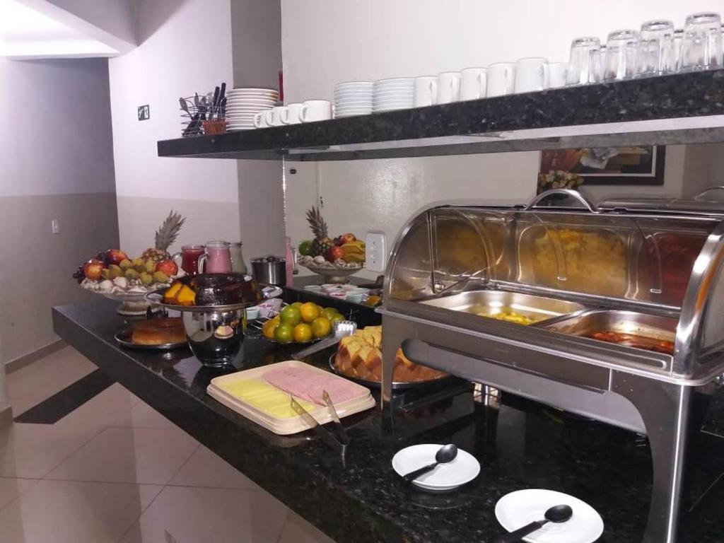 a kitchen with a buffet of food on a counter at Hotel Vila Real in Araçatuba