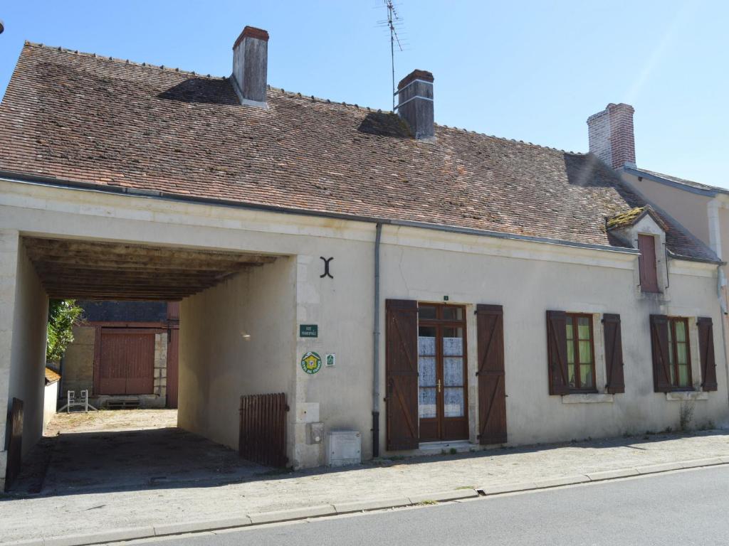 un antiguo edificio blanco con dos puertas de garaje en Gîte Neuillay-les-Bois, 3 pièces, 5 personnes - FR-1-591-104, en Neuillay-les-Bois