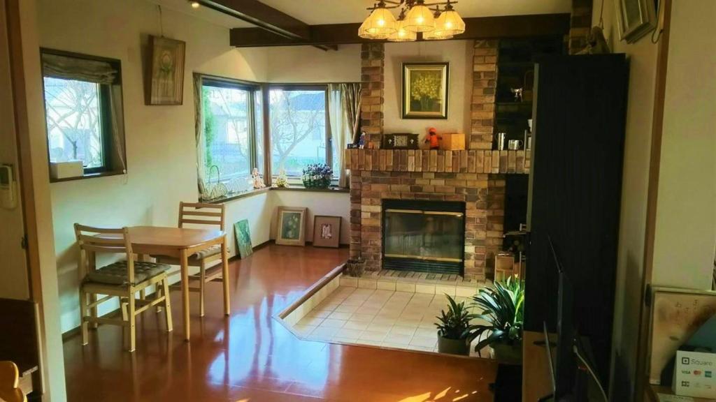 a living room with a fireplace and a table and chairs at AnBeeeNa in Akita