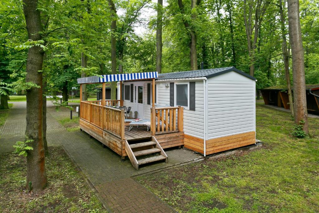 ein winziges Haus im Wald mit einer Veranda in der Unterkunft KNAUS Campingpark Hamburg in Hamburg