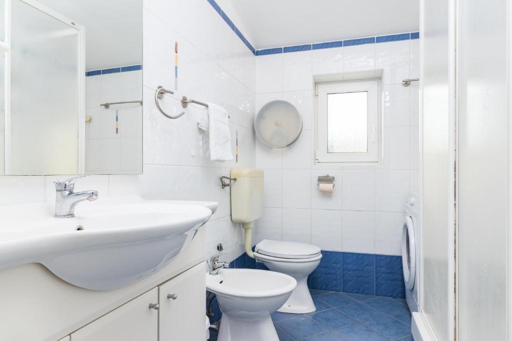 a white bathroom with a sink and a toilet at SEA VIEW APARTMENT in Ližnjan