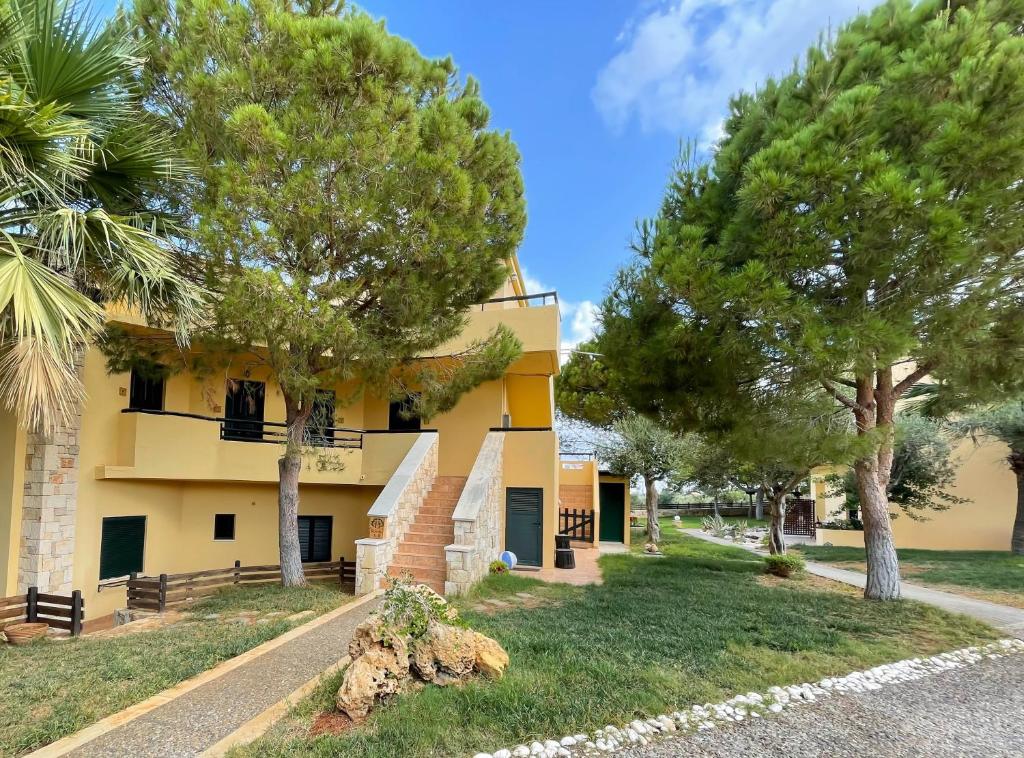 ein gelbes Gebäude mit Bäumen davor in der Unterkunft Kreta Natur in Hersonissos