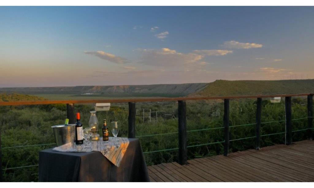 - une table avec des bouteilles de vin et des verres sur la terrasse dans l'établissement Kudu Ridge Game Lodge, à Addo