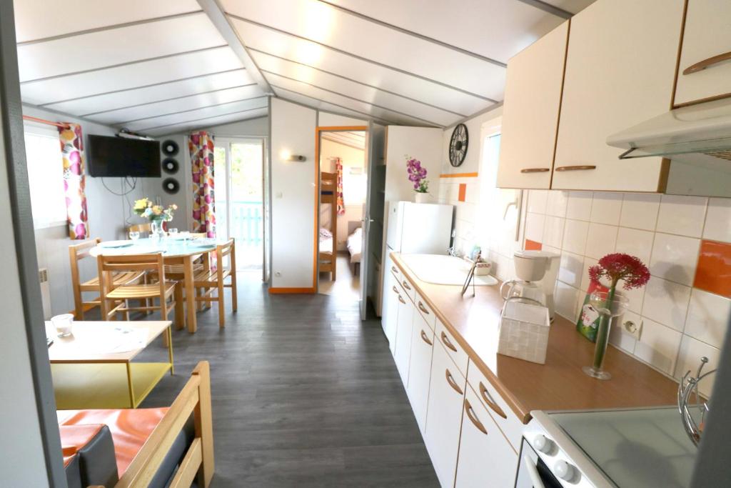 cocina con armarios blancos y comedor en Camping La Tentation, en Renty