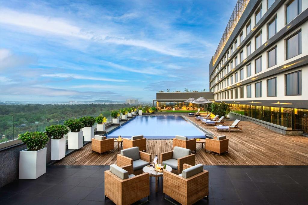 eine Hotelterrasse mit einem Pool, Tischen und Stühlen in der Unterkunft Vivanta Bhubaneswar DN Square in Bhubaneshwar