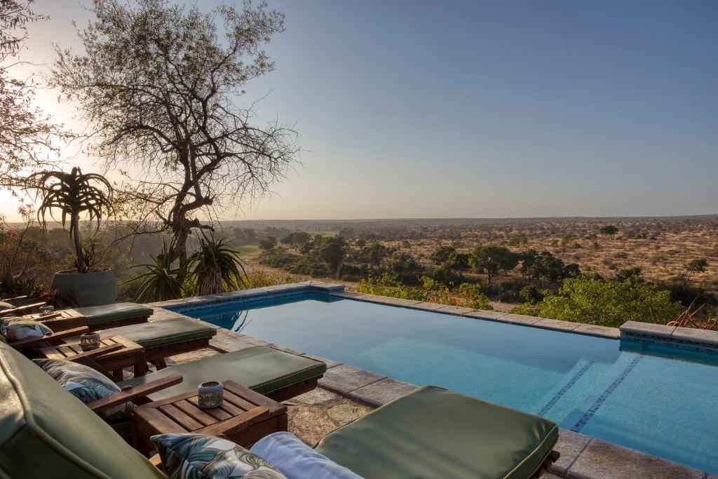 a swimming pool with chairs and a view of the desert at Klaserie Drift in Klaserie Private Nature Reserve