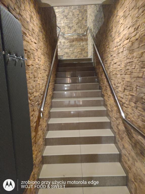 - un escalier dans un bâtiment avec un mur en pierre dans l'établissement Apartament "Good Night", à Nowy Dwór Gdański