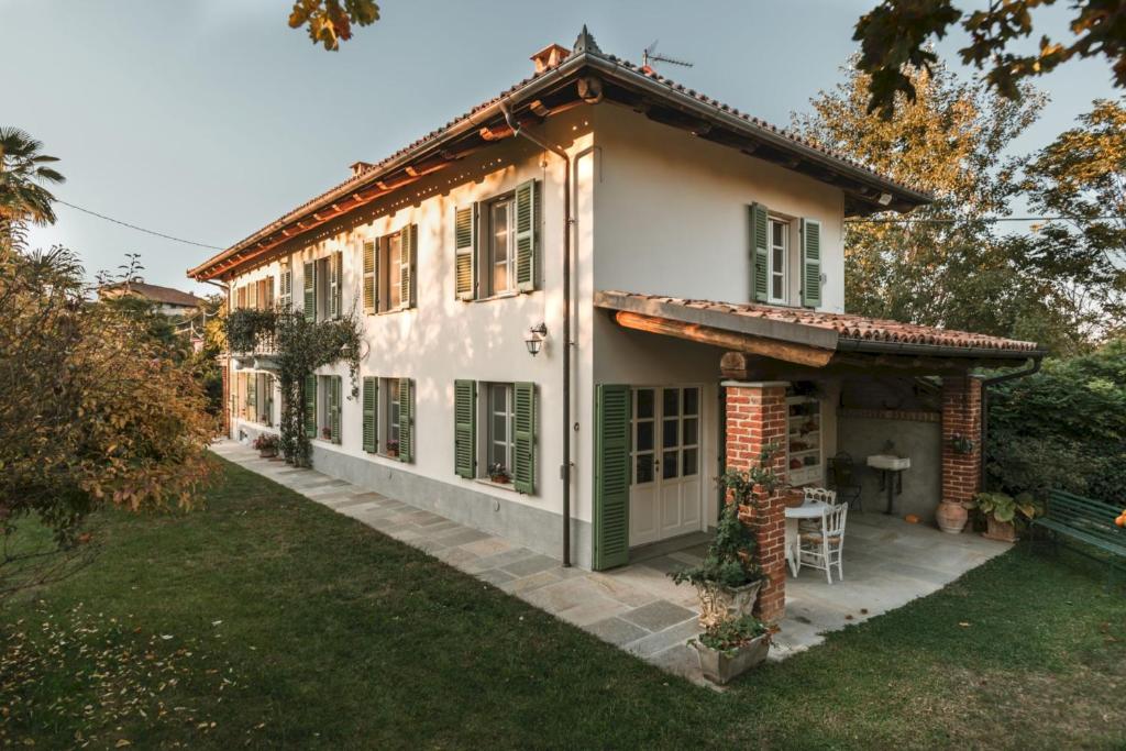 ein weißes Haus mit grünen Rollläden und einem Hof in der Unterkunft La Corte di Lu in Rocca D'Arazzo