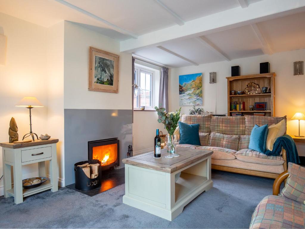 a living room with a couch and a fireplace at Whippet Cottage in Evesham