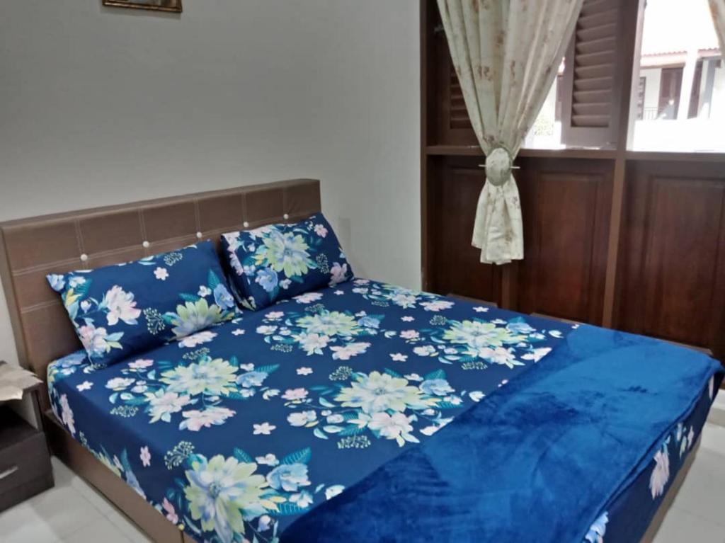 Un dormitorio con una cama azul con flores. en Rumah Melaka en Melaka