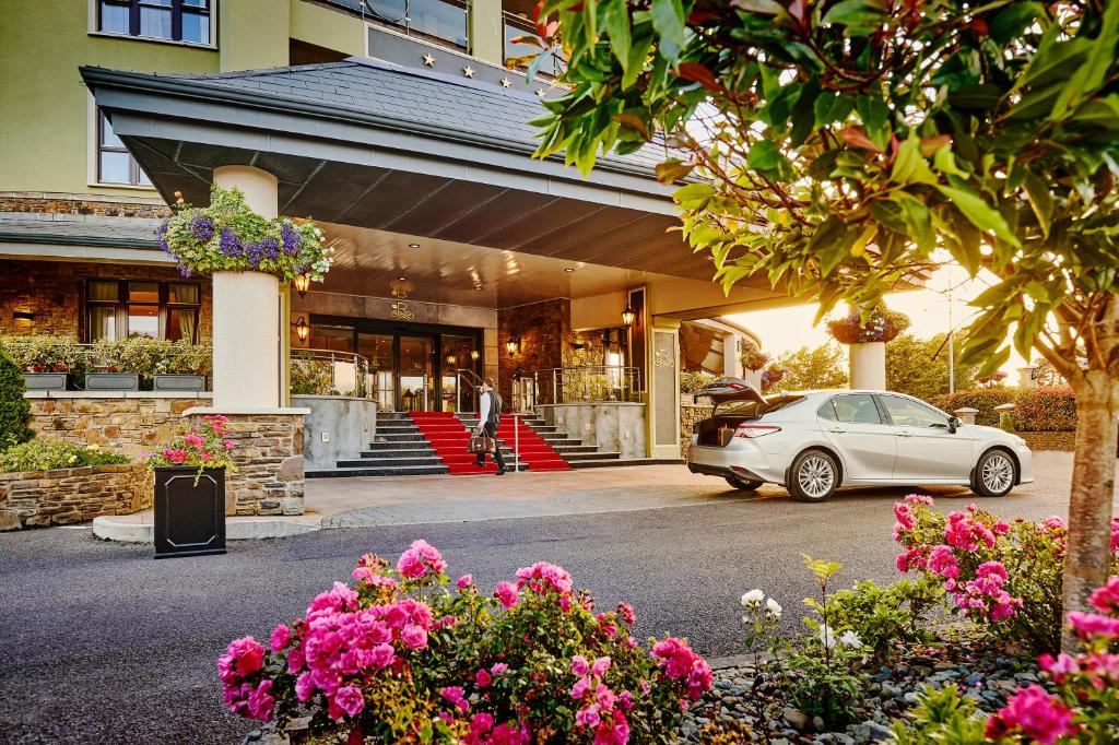 The Rose Hotel في ترالي: سيارة متوقفة أمام مبنى به زهور