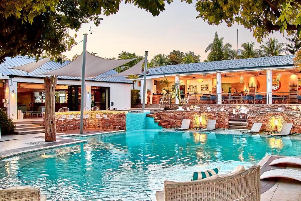 a swimming pool with chairs and a building at Lake Kariba Inns in Siavonga