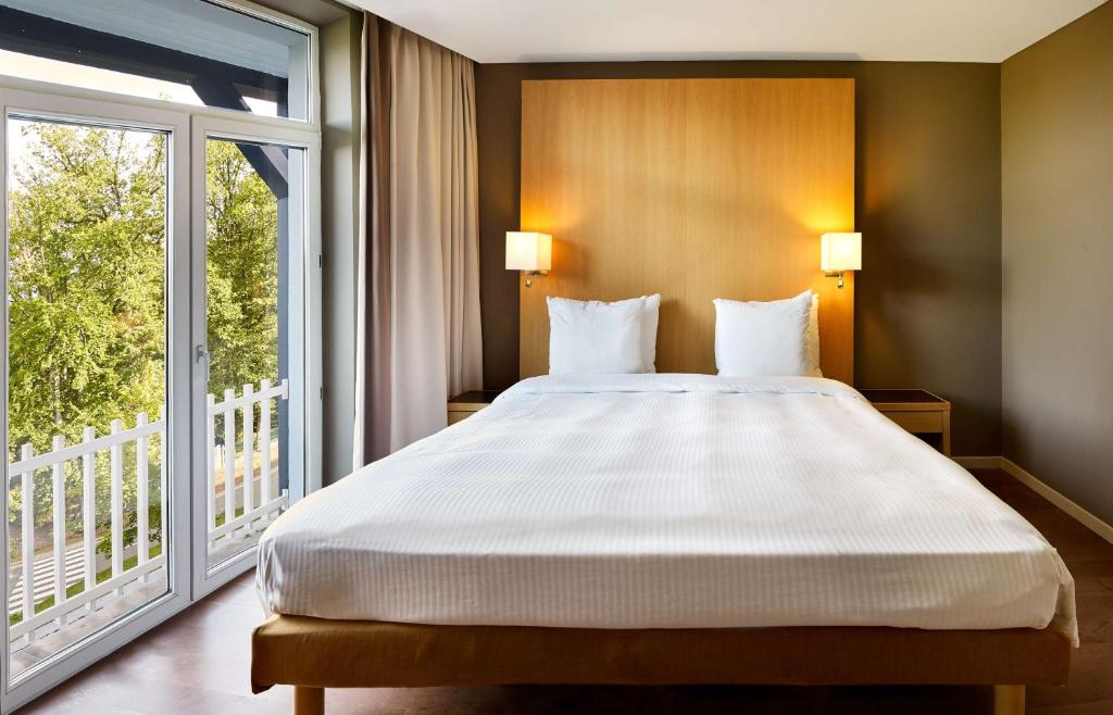 a bedroom with a large bed and a large window at Radisson BLU Balmoral in Spa