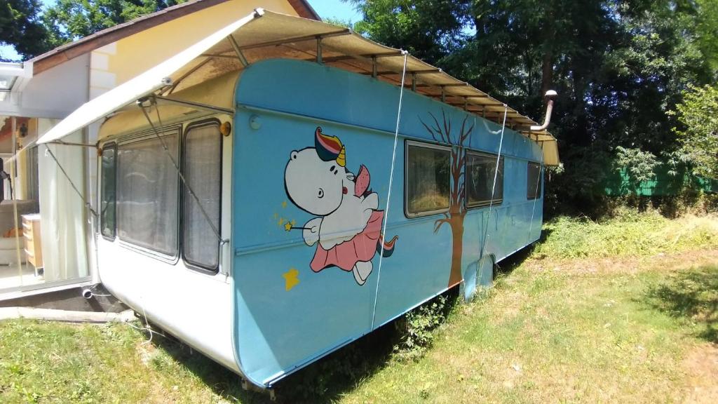 un vagón de tren azul con un gatito de hola pintado en él en Geräumiger Wohnwagen unter Bäumen neben Mur-Stausee en Feldkirchen bei Graz