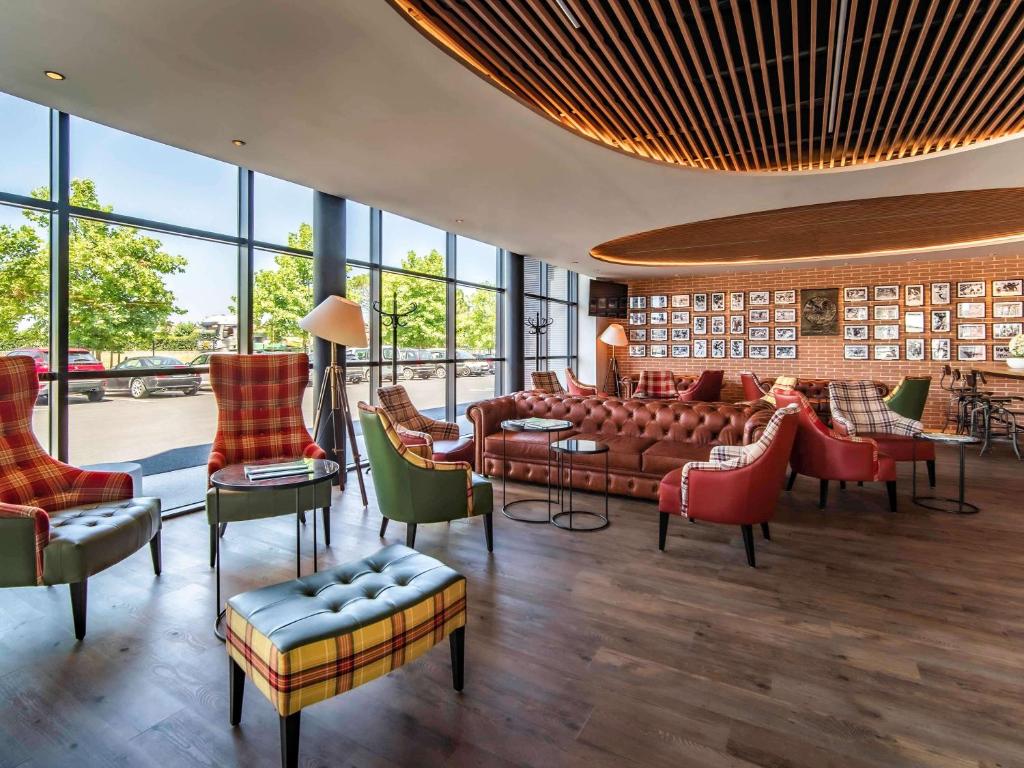 eine Lobby mit einem Sofa, Stühlen und Fenstern in der Unterkunft ibis Styles Castelnaudary in Castelnaudary