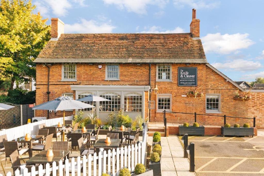 a brick building with tables and chairs in front of it at The Knife & Cleaver in Houghton Conquest