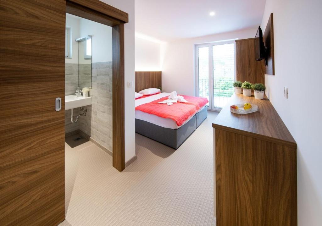 a bedroom with a red bed and a bathroom at Gostilna Pugelj in Novo Mesto