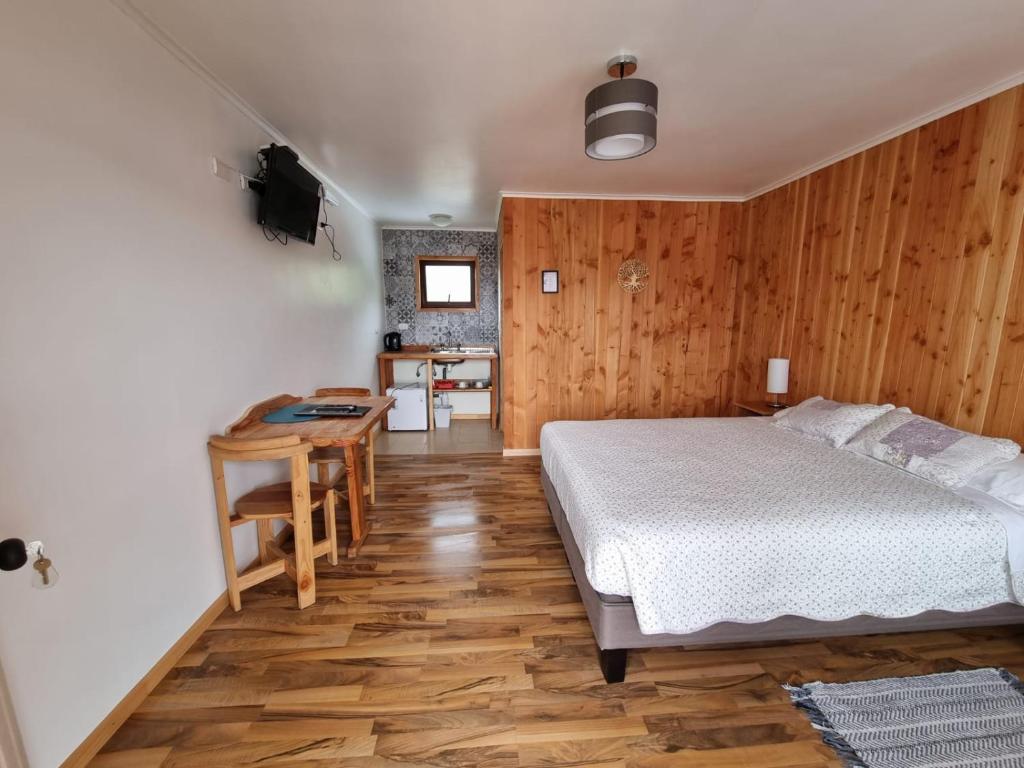 a bedroom with a bed and a table and a kitchen at Apart Hotel Antu de Villarrica in Villarrica