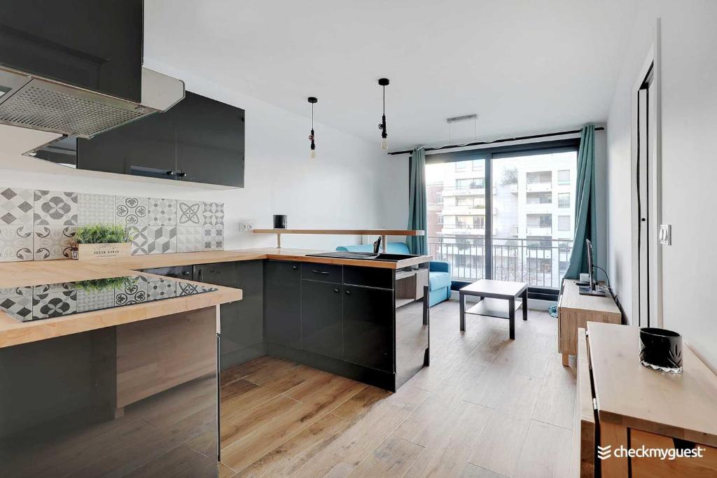 una cocina con armarios negros y una gran ventana en Cozy apartment - 1BR-4P - next to Paris, en Levallois-Perret