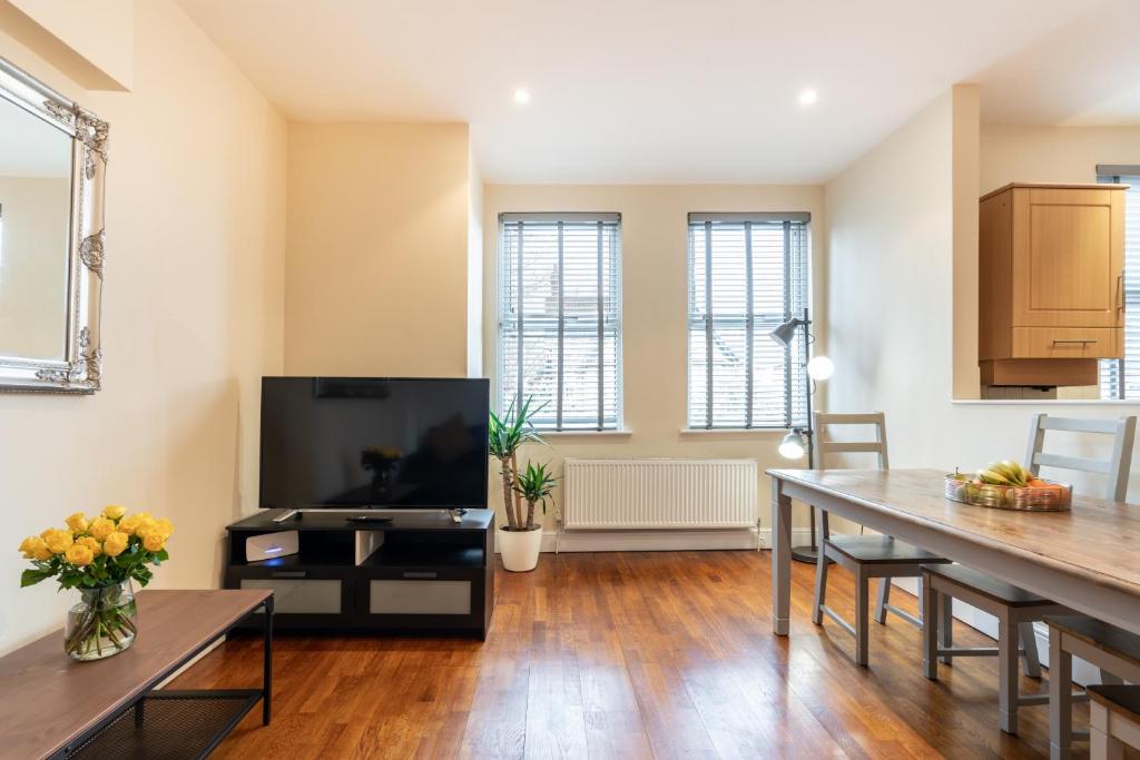 a living room with a table and a television at Luxury 2BDR duplex apt, N London, 2 floors in Enfield