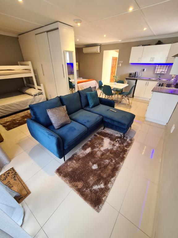 a living room with a blue couch and a kitchen at ARCHITECTS VIEW - VIP FAMILY SUITE in Durban