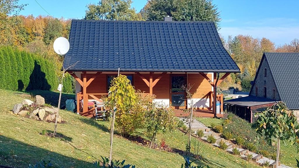 une cabane en rondins avec un toit noir dans l'établissement Zielony Zakątek koło Karpacza, à Sosnówka