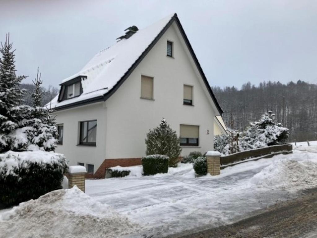 ein weißes Haus mit Schnee auf dem Boden in der Unterkunft Ferienhaus Sommerhaus-Sauerland in Hachen