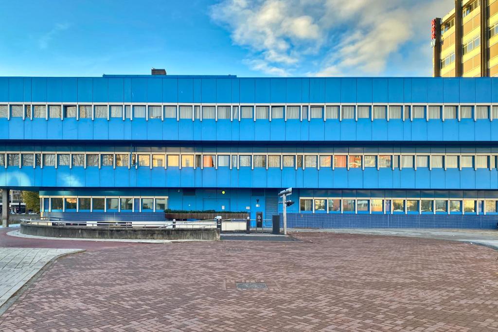 ein blaues Gebäude mit einer Bank davor in der Unterkunft XO Hotels Blue Square in Amsterdam