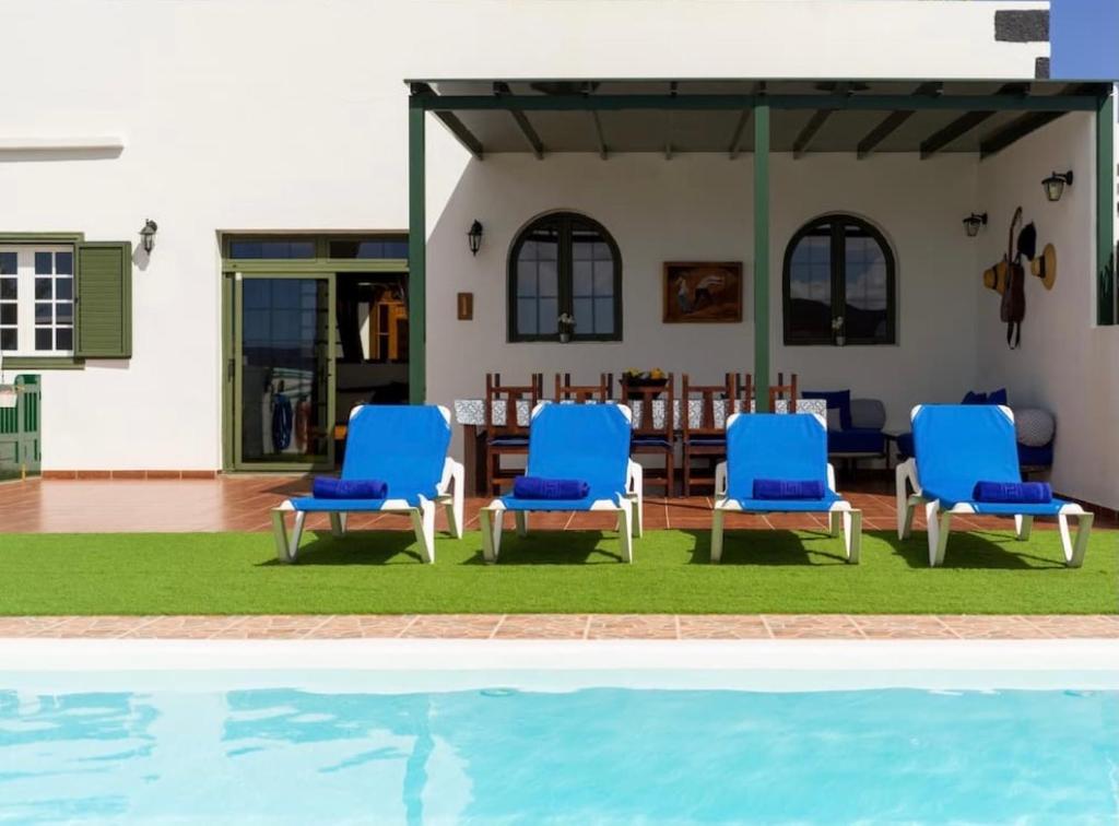 un grupo de sillas azules sentadas junto a una piscina en Pico Partido villa, en Tinguatón