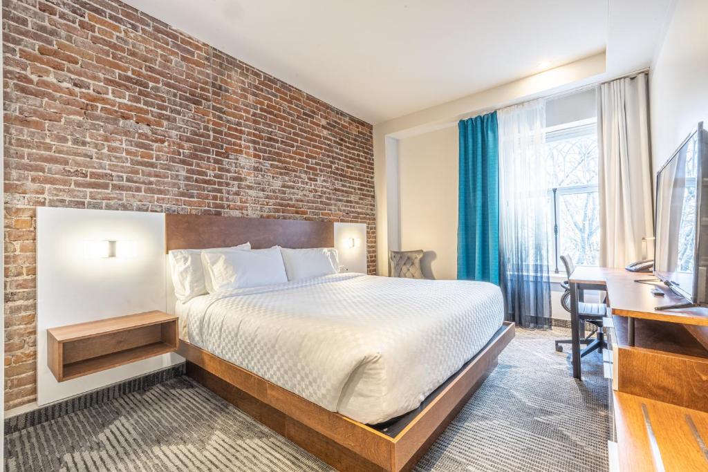 une chambre d'hôtel avec un lit et un mur en briques dans l'établissement Hôtel Manoir Vieux-Québec, à Québec