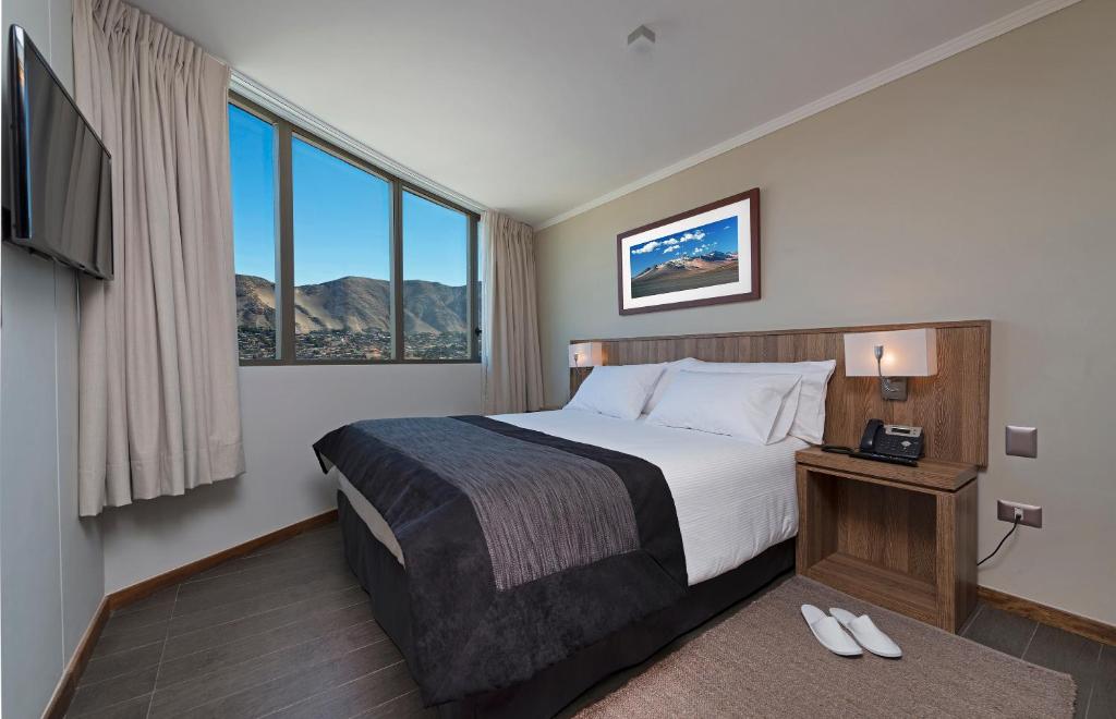 Una habitación de hotel con una cama y una ventana grande. en Hotel Atacama Suites, en Copiapó