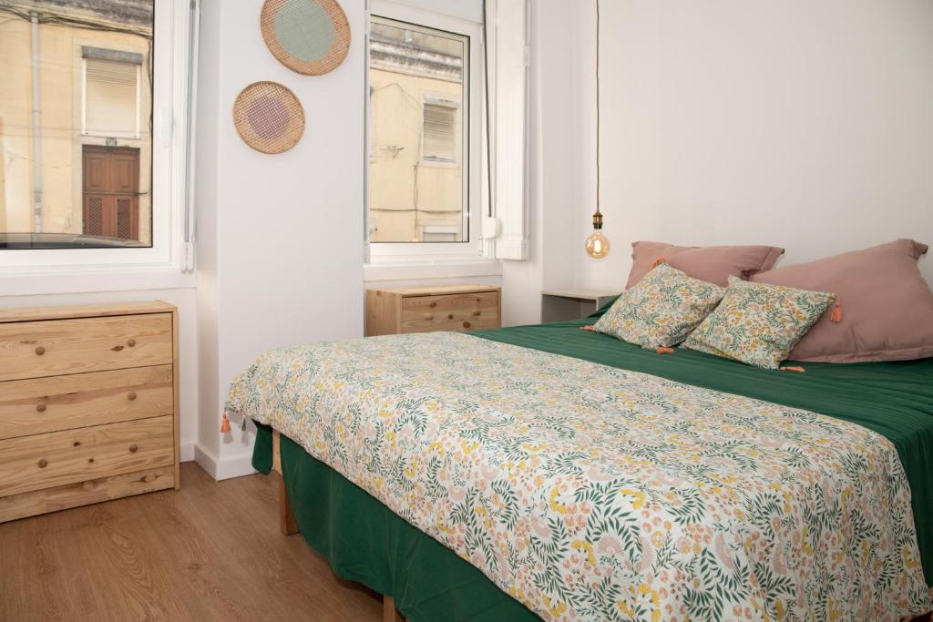 a bedroom with a bed with a green comforter and two windows at Charming 1 Bedroom Apartment w/ Terrace Near Belém in Lisbon
