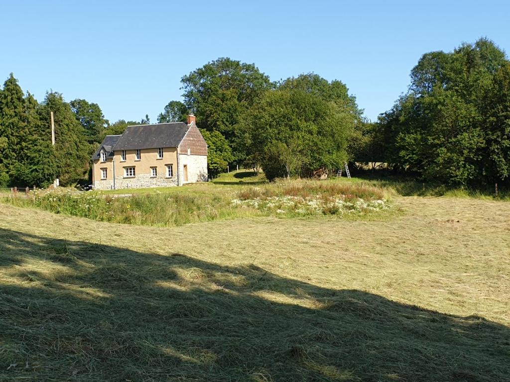 une vieille maison sur un champ herbeux devant les arbres dans l'établissement La fermette - chambres d'hôtes dans environnement calme et arboré, à Saint-Jean-des-Baisants