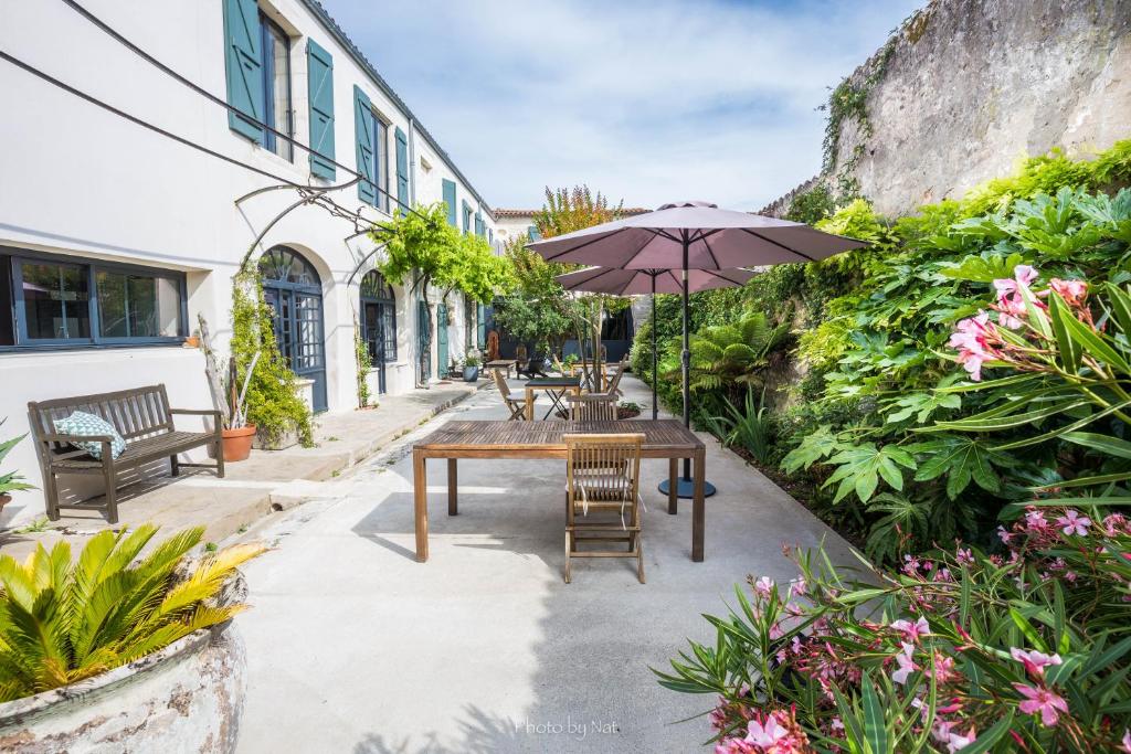 a patio with a wooden table and an umbrella at L’Ostréale in La Tremblade
