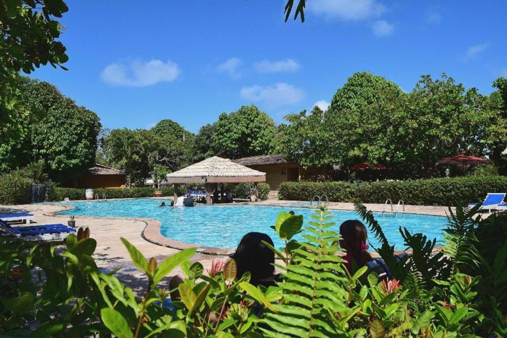 um grupo de pessoas sentadas em frente a uma piscina em Pousada do Forte em Barra do Cunhaú