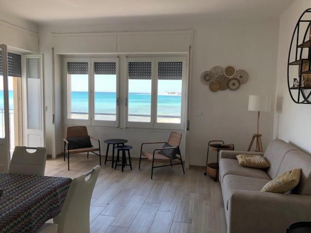 ein Wohnzimmer mit einem Sofa, Stühlen und Meerblick in der Unterkunft Viva Vista Mare Trilo Primo Piano in Porto Cesareo