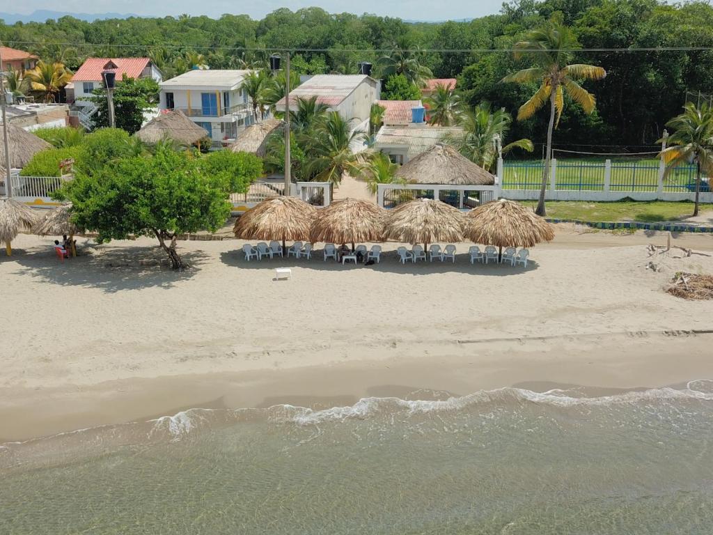 una playa con sillas y sombrillas de paja en la arena en Hotel Cabaña Playa DanRay, en Coveñas