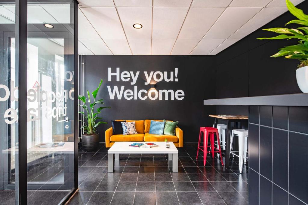 a lobby with a couch and a welcome sign on the wall at City Trip Hostels Amsterdam-Purmerend in Purmerend